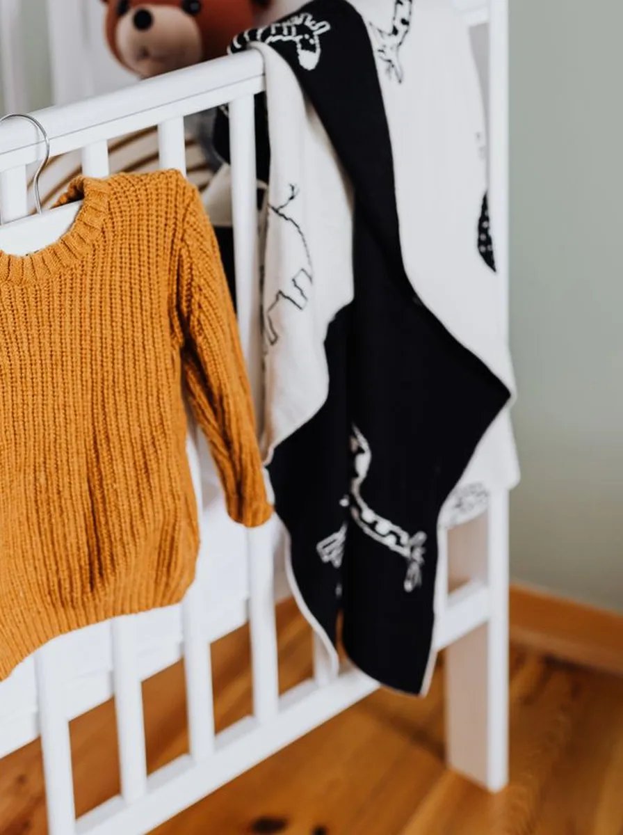 White crib with mustard baby clothes