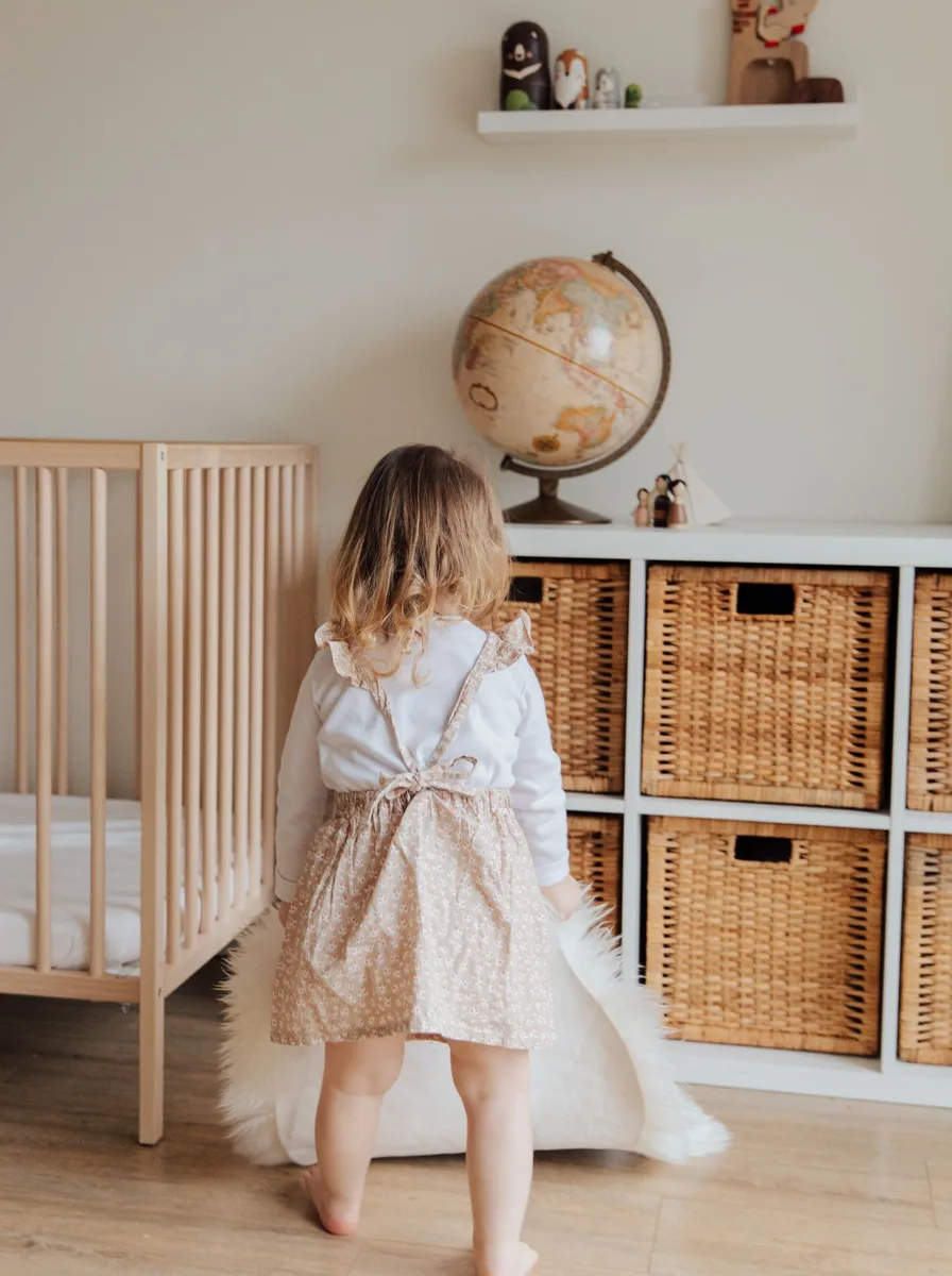 Girl standing by a crib with a globe