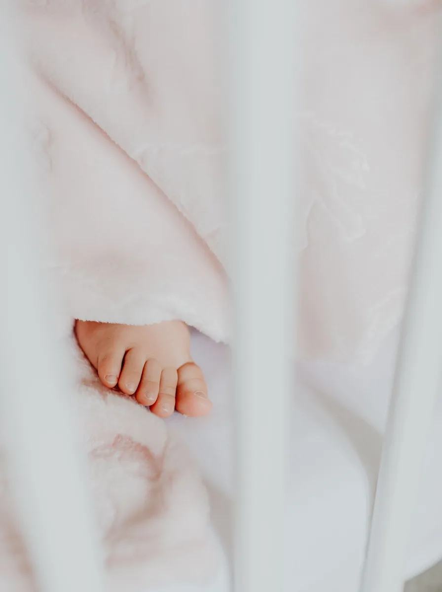 Baby feet on soft white bedding