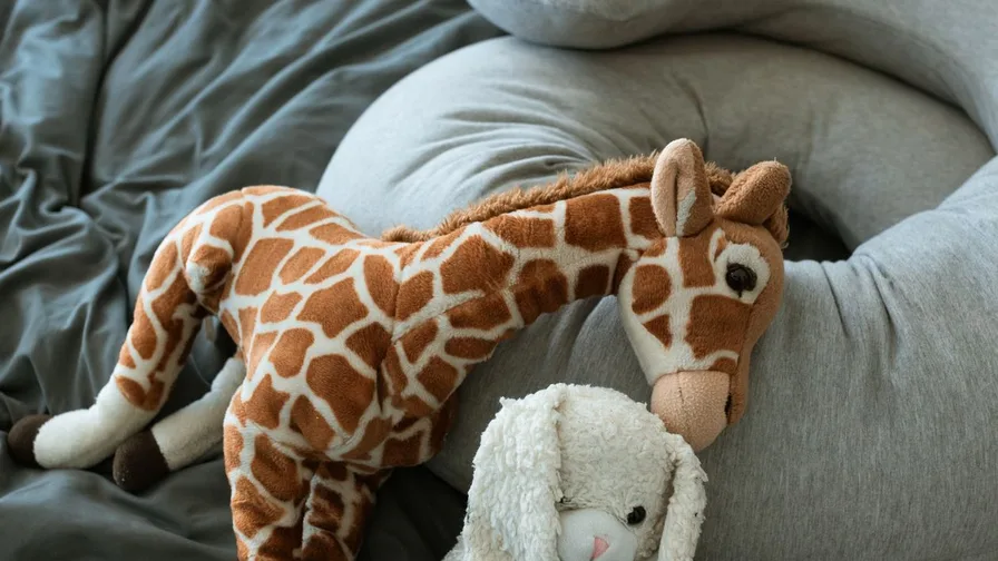 Giraffe and bunny plush toys on a bed
