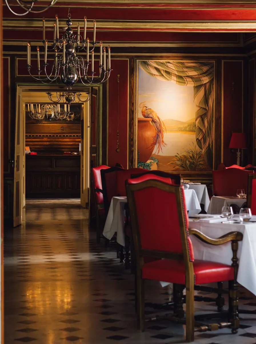 Dramatic tavern-style dining room with red panels and an oversized mural