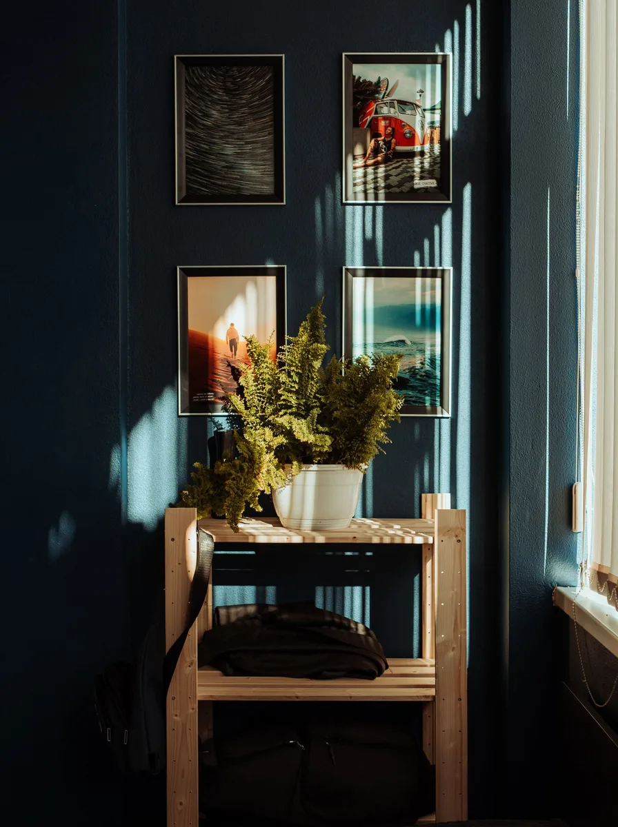 Dark hallway corner with small framed pictures and a wooden shelf