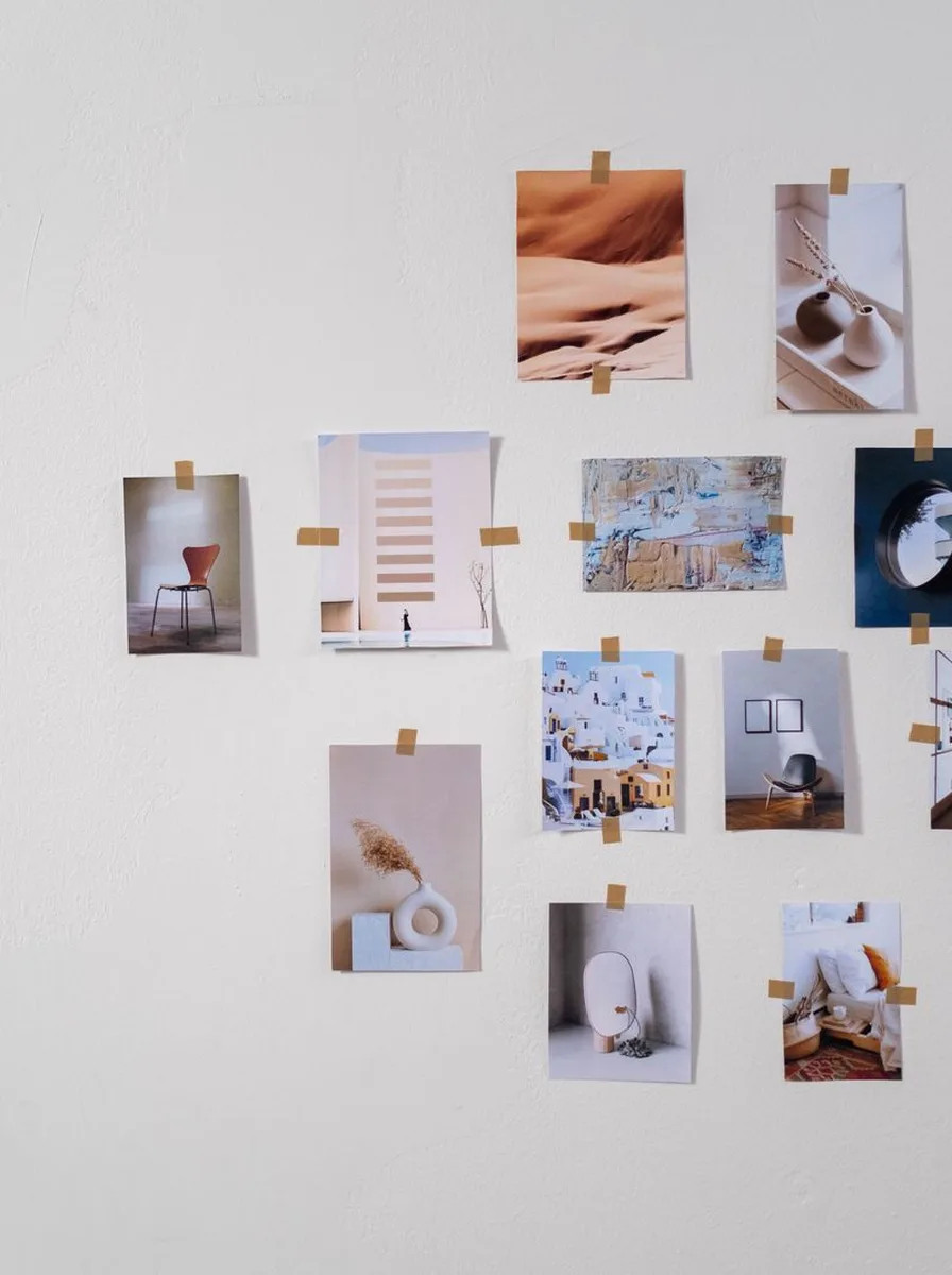 White wall with small photos taped in a scattered arrangement