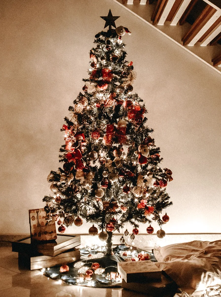 Tall decorated Christmas tree beside a staircase