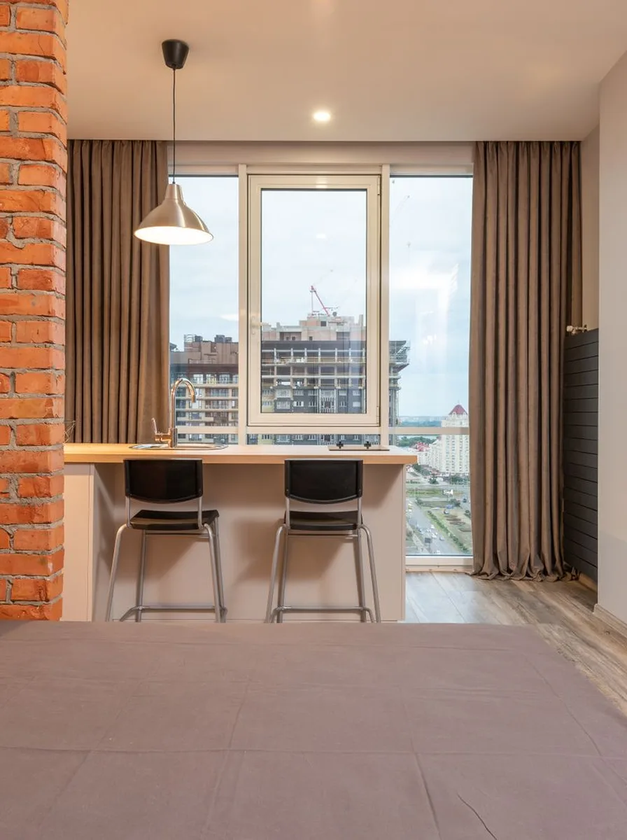 Oversized mirror opposite window doubling light in tiny flat