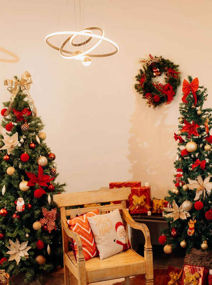 Two Christmas trees with red ornaments and a chair