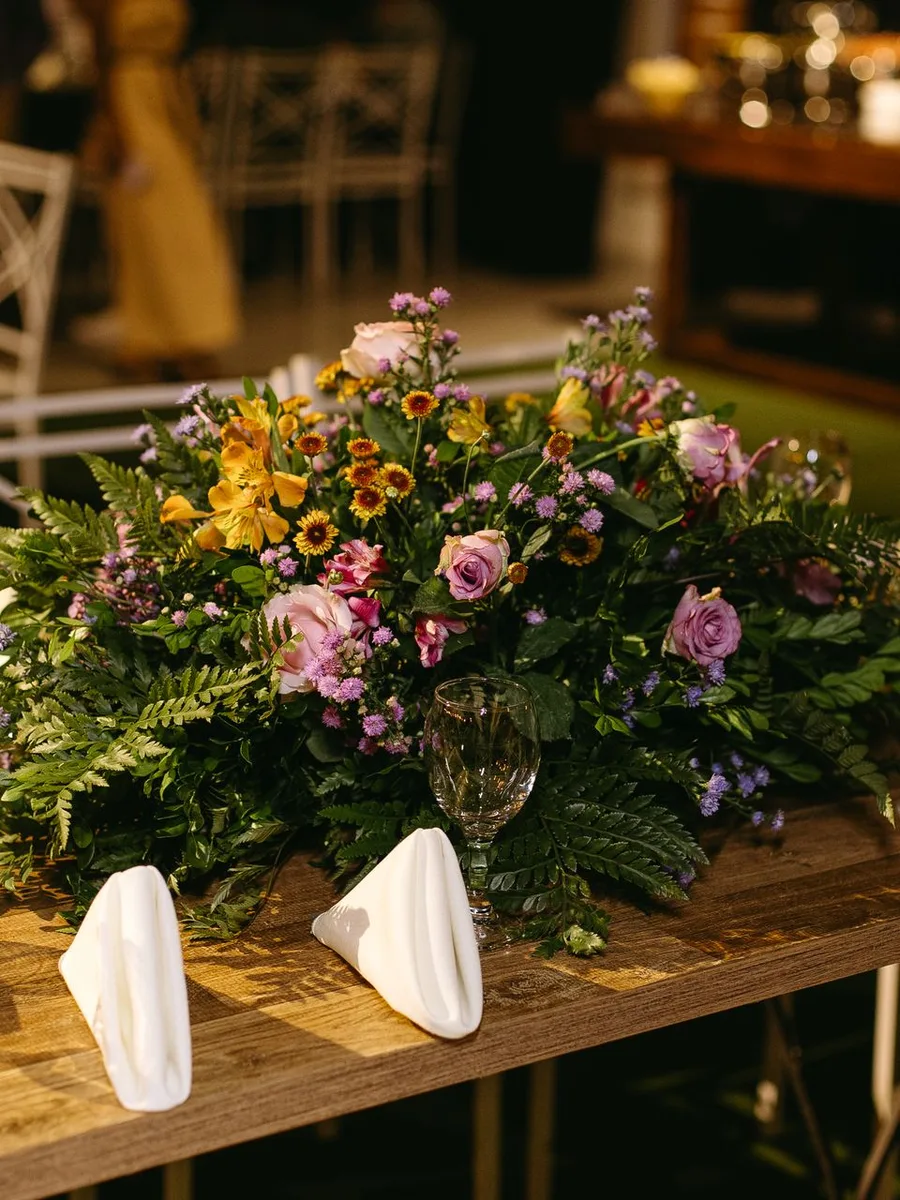 Footed vase of ranunculus flowers on a dining table